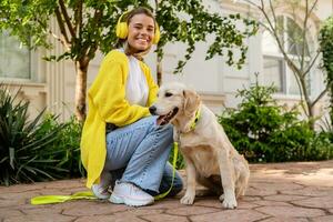 gelukkig glimlachen vrouw in geel trui wandelen Bij haar huis met een hond gouden retriever foto