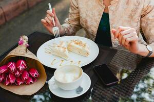 jong elegant vrouw zittend in cafe, aan het eten smakelijk taart foto