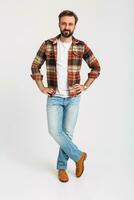 knap gebaard Mens in hipster kleding gekleed in jeans en geruit overhemd foto