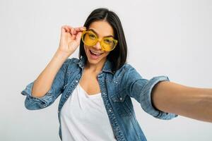 aantrekkelijk vrouw gekleed jeans en denim overhemd vervelend geel zonnebril foto