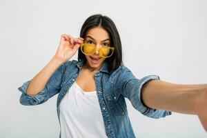 aantrekkelijk vrouw gekleed jeans en denim overhemd vervelend geel zonnebril foto