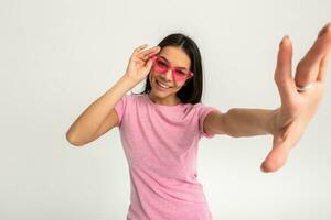 aantrekkelijk vrouw in roze t-shirt en zonnebril foto