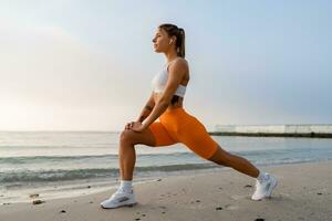 mooi jong glimlachen vrouw aan het doen sport- in de ochtend- in elegant sport kleding sportkleding, mager sterk lichaam, gezond fit levensstijl foto