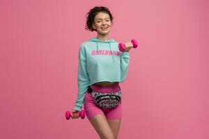glimlachen gelukkig mooi vrouw in elegant sport- kleding aan het doen training Aan roze achtergrond geïsoleerd in studio foto