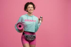 glimlachen gelukkig mooi vrouw in elegant sport- kleding poseren Aan roze achtergrond geïsoleerd in studio foto