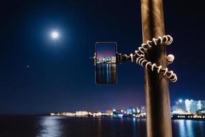 een smartphone gebruiken op een opvouwbaar statief met lange blootstelling aan de zee 's nachts foto