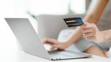 jonge vrouw met creditcard en laptopcomputer gebruikt. online winkelen, internetbankieren, e-commerce, geld uitgeven, thuiswerken concept
