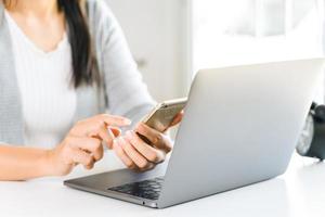 jonge vrouw met behulp van mobiele telefoon met laptopcomputer. foto