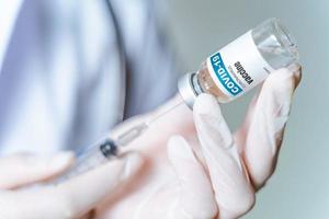 de arts die een spuit met covid-19-vaccins in een glazen fles vasthoudt. covid-19 corona virus behandelingsconcept.