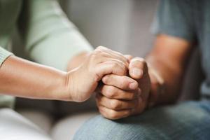 vrouwelijke vriend of familie zitten en houden elkaars hand vast tijdens het opvrolijken van de mentaal depressieve man, psycholoog biedt mentale hulp aan de patiënt. ptss geestelijke gezondheidsconcept