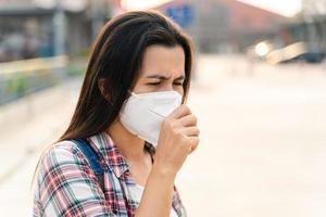 aziatische vrouw die n95-masker draagt om vervuiling pm2.5 en virus te beschermen. covid-19 coronavirus en luchtvervuiling pm2.5 concept. foto