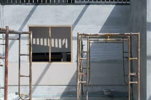 zonlicht en schaduw Aan oppervlakte van houten venster kader Aan beton muur met de oud stellingen binnen van huis bouw plaats foto