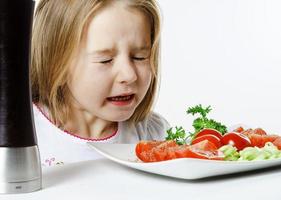 schattig klein meisje met salade en peperdoos foto