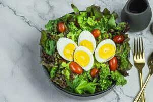 een kom van salade met eieren, tomaten en sla foto