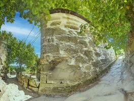 panoramisch afbeelding langs voetpad met overwoekerd oud natuurlijk steen muur foto