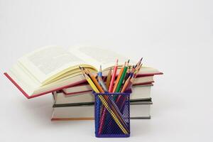 krijt of gekleurde potloden in doos en de boek geplaatst in de wazig achtergrond. kennis en onderwijs concept. foto