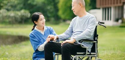 ouderen Aziatisch senior Mens Aan rolstoel met Aziatisch voorzichtig verzorger en aanmoedigen geduldig, wandelen in tuin. met zorg van een verzorger en senior Gezondheid verzekering. foto