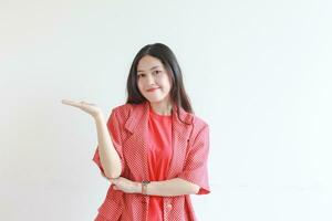 portret van mooi Aziatisch vrouw vervelend rood kleding met hand- gebaar presenteren iets of kopiëren ruimte foto