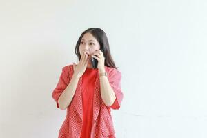 portret van mooi Aziatisch vrouw vervelend rood kleding terwijl roeping met verrast uitdrukking foto