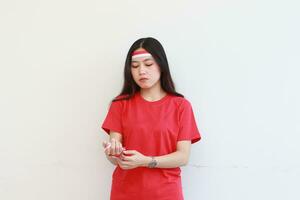 portret van een Aziatisch vrouw vervelend een rood kleding koppelverkoop haar handen met een vlag lint foto