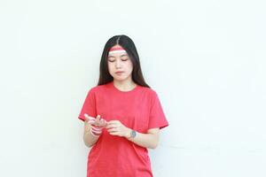 portret van een Aziatisch vrouw vervelend een rood kleding koppelverkoop haar handen met een vlag lint foto