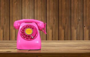 oud fashioned roze bureau telefoon Aan houten tafel geïsoleerd met houten muur net zo achtergrond. foto