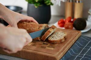 vrouw snijdend brood van brood met groot mes foto