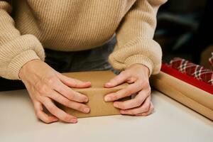 vrouw verpakking geschenk doos in ambacht papier, Cadeau voor Kerstmis verrassing foto