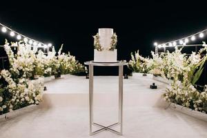 witte bruidstaart op een hoge tribune dichtbij het witte podium foto