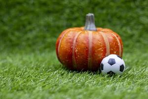 voetbal met pompoen is op groen gras foto