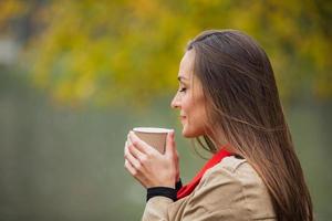 brunette vrouw met kopje koffie in het herfstpark.