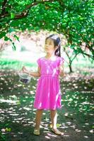 klein Aziatisch meisje op zoek naar de moerbeivrucht in de tuin