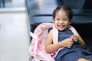 klein Aziatisch meisje met rugzak liggend op de bank klaar terug naar school