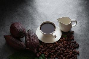 warme chocolademelk en cacaopeul gesneden bloot cacaozaden op donkere tafel, bovenaanzicht met kopieerruimte foto
