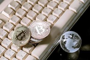 glazen bol en bitcoin cryptocurrency op toetsenbord. bedrijfsconcept foto