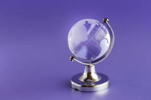 globe is gemaakt van glas op een paarse achtergrond. glazen bol. globaliseringsconcept foto
