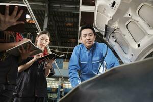 Aziatisch mannetje professioneel automotive ingenieur leidinggevende beschrijft auto motor onderhoud en reparatie werk met monteur arbeider personeel team in fix onderhoud garage, specialist beroepen in auto industrie. foto