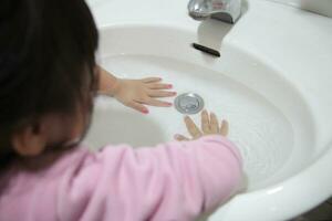 Aziatisch kind beoefenen mooi zo hygiëne hand- het wassen Bij wastafel naar voorkomen foto