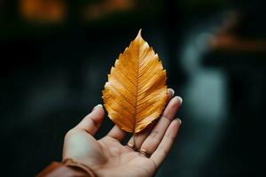 hand- voorzichtig houdt een gouden blad, een symbool van herfst vluchtig schoonheid ai gegenereerd foto