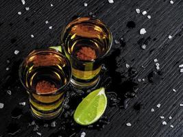 twee shots tequila goud met sappige limoen en zeezout foto