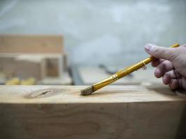 man's hand houdt borstel voor lijm op houten balken foto