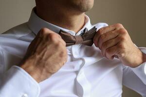 bruidegom krijgen klaar voor zijn bruiloft en aanscherping zijn stropdas foto