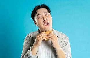 portret van Aziatisch Mens aan het eten snel voedsel Aan blauw achtergrond foto