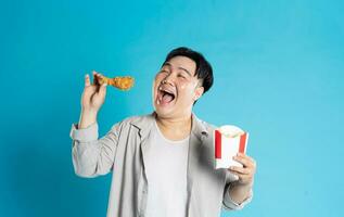 portret van Aziatisch Mens aan het eten snel voedsel Aan blauw achtergrond foto