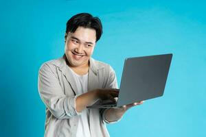 beeld van Aziatisch Mens gebruik makend van laptop Aan blauw achtergrond foto