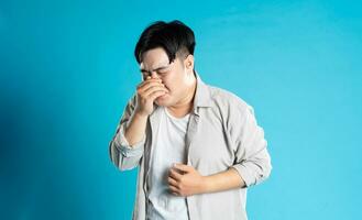 beeld van Aziatisch Mens hebben Gezondheid problemen, geïsoleerd Aan blauw achtergrond foto