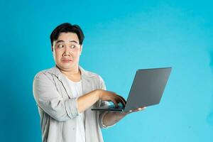 beeld van Aziatisch Mens gebruik makend van laptop Aan blauw achtergrond foto