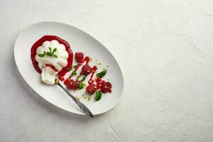 lepel met een stuk van panna cotta met siroop, frambozen en munt in ovaal bord, voedsel stijl foto