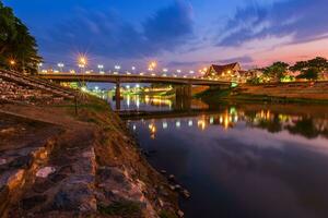 natuurlijke avond met uitzicht op de nan-rivier en de naresuan-brug in het park om te ontspannen wandelen, joggen en sporten bij zonsondergang in de stad phitsanulok, thailand. foto