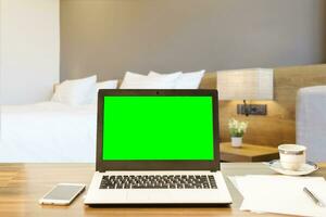 laptop, slim telefoon en document Aan houten tafel van onscherp wit hoofdkussen Aan bed decoratie met licht lamp in hotel slaapkamer interieur achtergrond, vrije tijd en reizen in de vakantie concept. foto